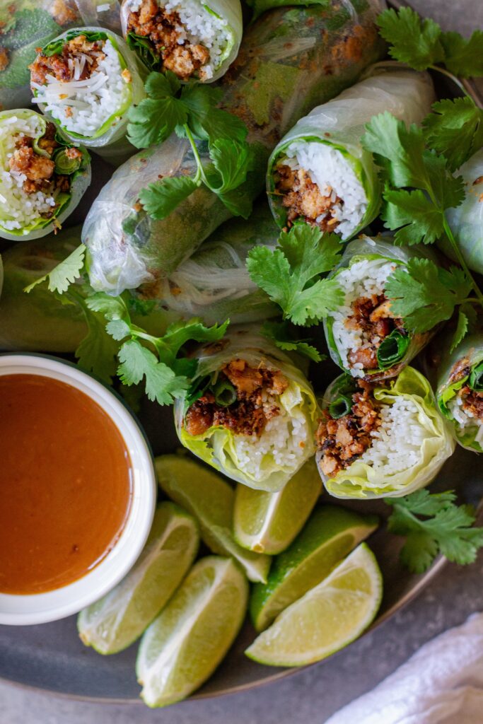 Fresh lemongrass tofu rice paper rolls cut in half with peanut sauce on the side