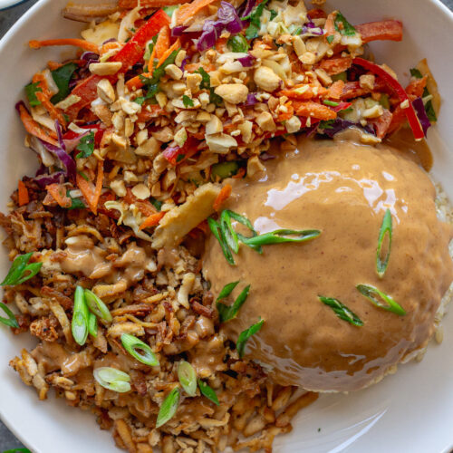 Bowl of crispy shredded tofu peanut bowls with creamy peanut sauce and colorful slaw, garnished with green onion and crushed peanuts.