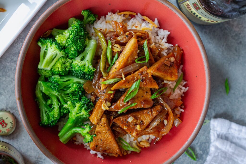 Golden crispy tofu adobo served over steamed white rice and a side of broccoli in a bowl