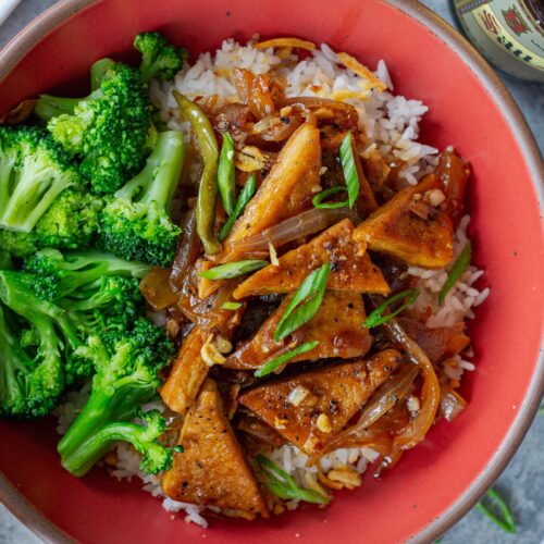 Golden crispy tofu adobo served over steamed white rice and a side of broccoli in a bowl