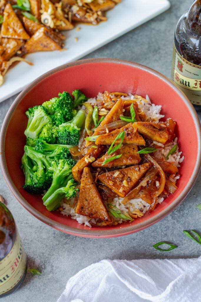 Golden crispy tofu adobo served over steamed white rice and a side of broccoli in a bowl