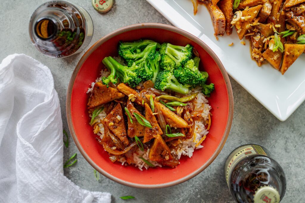 Golden crispy tofu adobo served over steamed white rice and a side of broccoli in a bowl