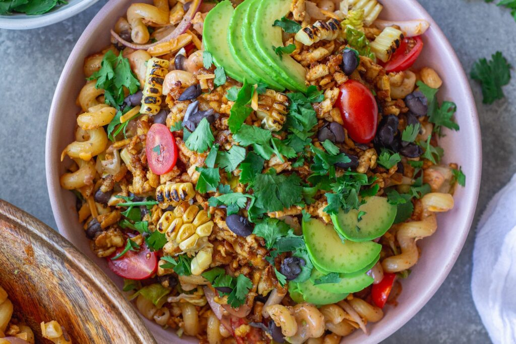 Vegan BBQ chicken pasta salad in a large bowl with crispy tofu, colorful vegetables, and creamy BBQ ranch dressing