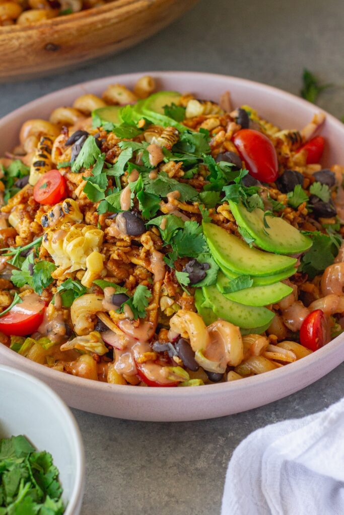 Vegan BBQ chicken pasta salad in a large bowl with crispy tofu, colorful vegetables, and creamy BBQ ranch dressing