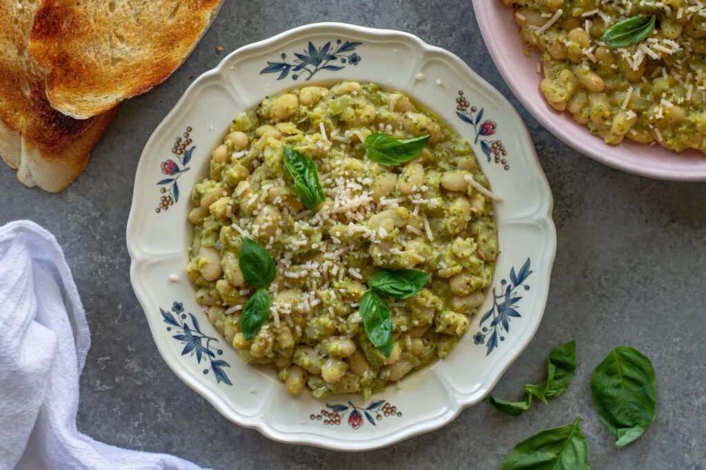 Creamy pea pesto white bean skillet on a serving plate garnished with fresh basil and vegan parmesan