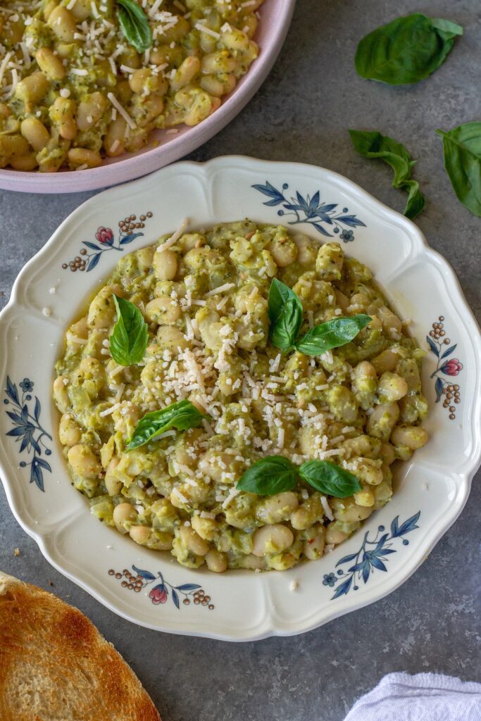 Creamy pea pesto white bean skillet on a serving plate garnished with fresh basil and vegan parmesan