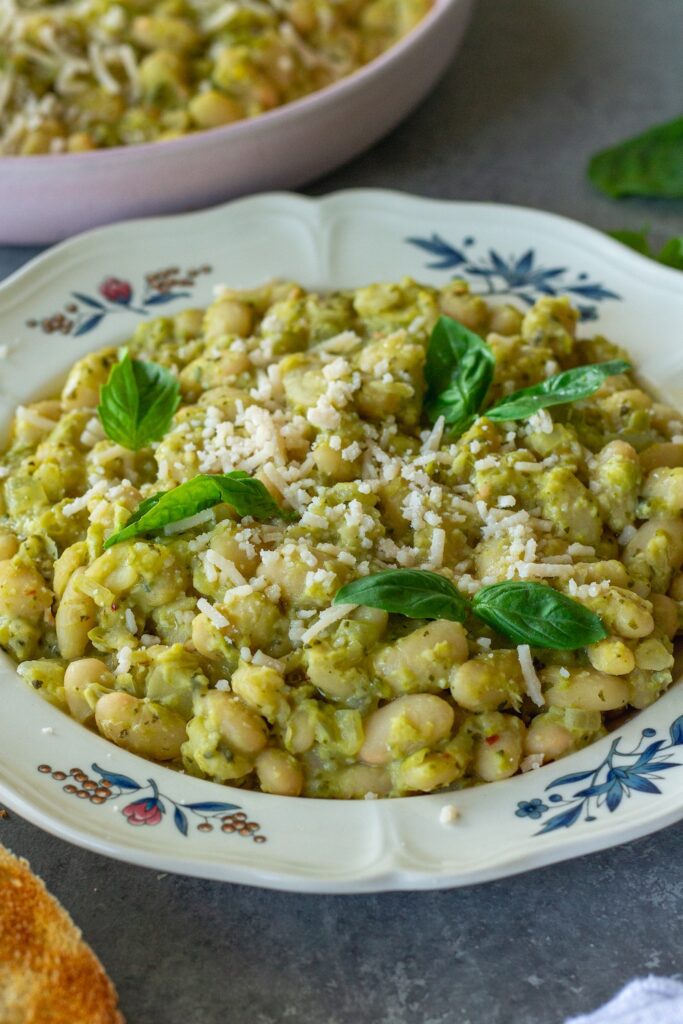 Creamy pea pesto white bean skillet on a serving plate garnished with fresh basil and vegan parmesan
