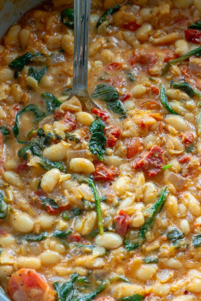 close-up of creamy tuscan white bean skillet topped with parmesan and parsley