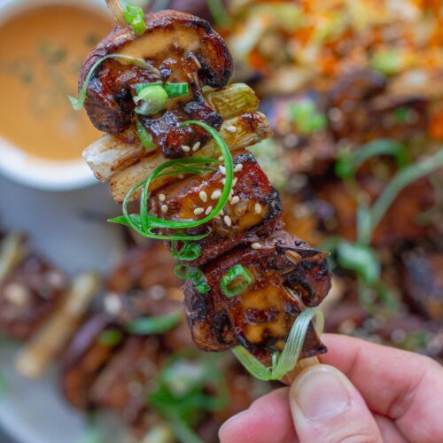 Golden grilled Korean BBQ tofu skewers with mushrooms and scallions on bamboo skewers, served with a side of Gochujang mayonnaise and garnished with sesame seeds and green onions