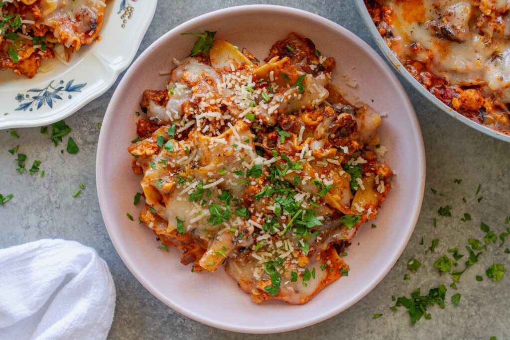 Vegan skillet lasagna served on a plate, showing the tender noodles mixed with the saucy filling, topped with melted vegan cheese and fresh parsley.