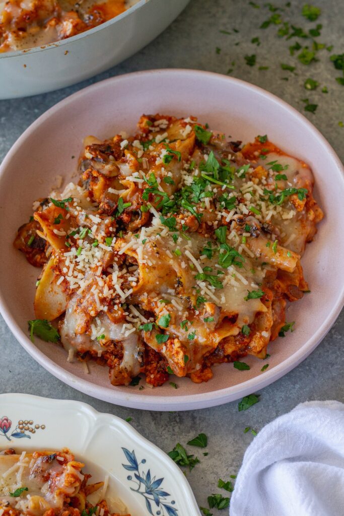 Vegan skillet lasagna served on a plate, showing the tender noodles mixed with the saucy filling, topped with melted vegan cheese and fresh parsley.