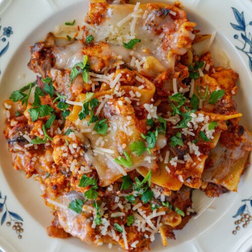 Vegan skillet lasagna served on a plate, showing the tender noodles mixed with the saucy filling, topped with melted vegan cheese and fresh parsley.