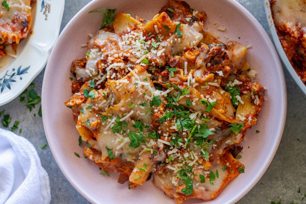 Vegan skillet lasagna served on a plate, showing the tender noodles mixed with the saucy filling, topped with melted vegan cheese and fresh parsley.