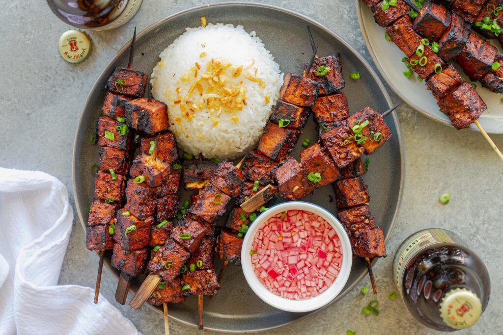 Filipino-style vegan BBQ tofu skewers glazed and charred, served with garlic rice and Filipino spiced vinegar