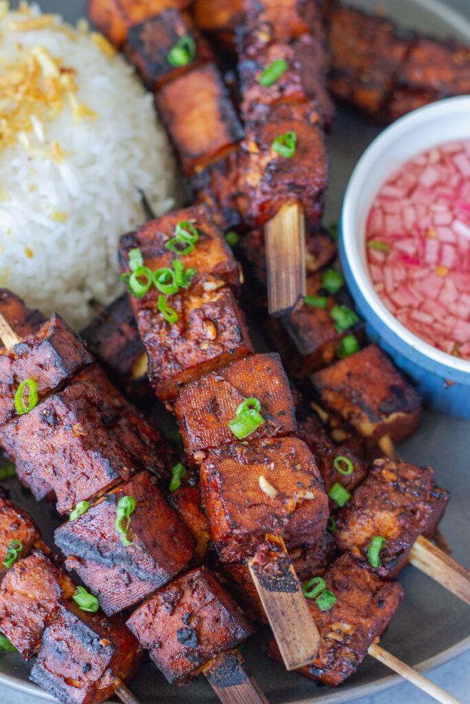 Filipino-style vegan BBQ tofu skewers glazed and charred, served with garlic rice and Filipino spiced vinegar