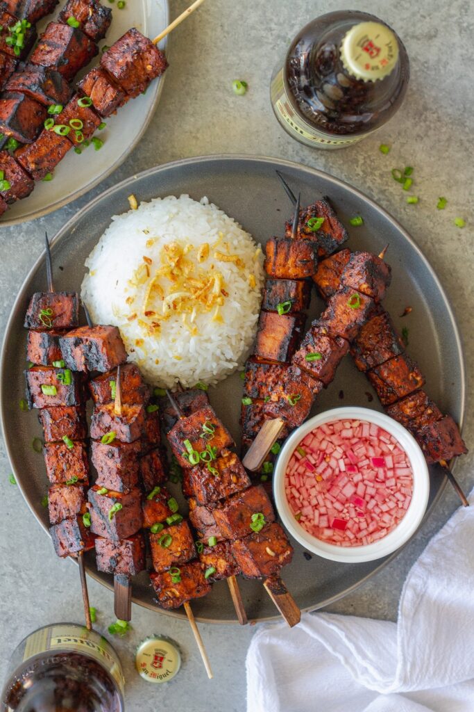 Filipino-style vegan BBQ tofu skewers glazed and charred, served with garlic rice and Filipino spiced vinegar