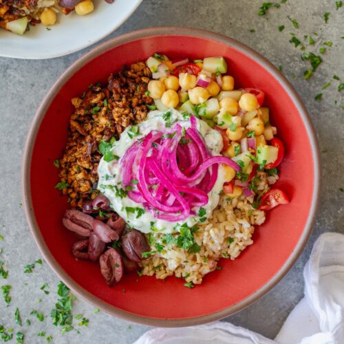 Mediterranean-inspired tofu bowl with crispy seasoned tofu, chickpea salad, rice, Kalamata olives, vegan tzatziki and pickled red onions