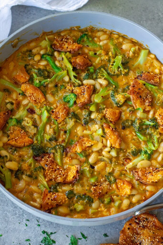 Creamy vegan skillet broccoli cheddar beans topped with golden cheese crisps