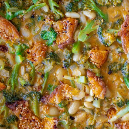Creamy vegan skillet broccoli cheddar beans topped with golden cheese crisps