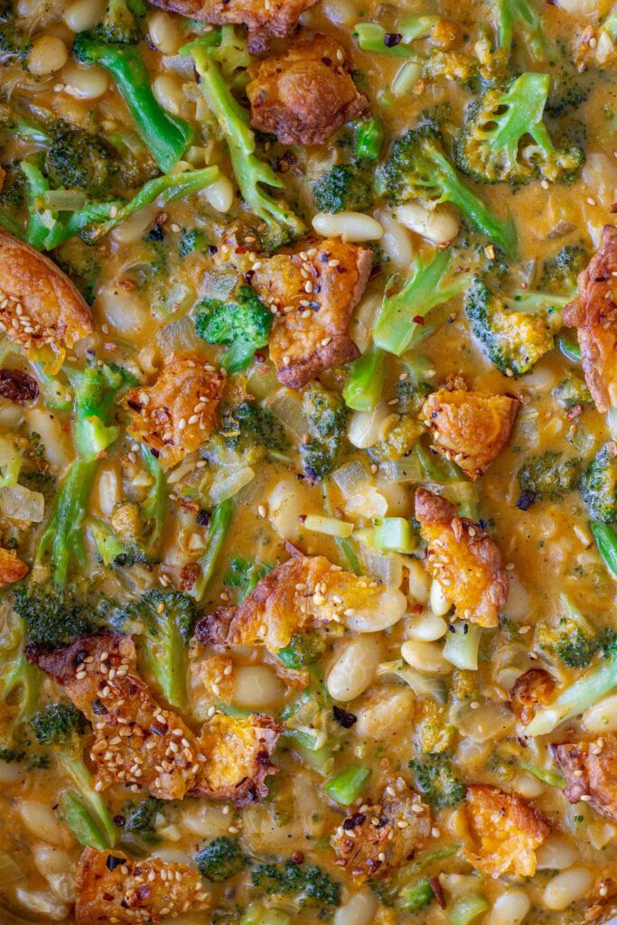 Creamy vegan skillet broccoli cheddar beans topped with golden cheese crisps