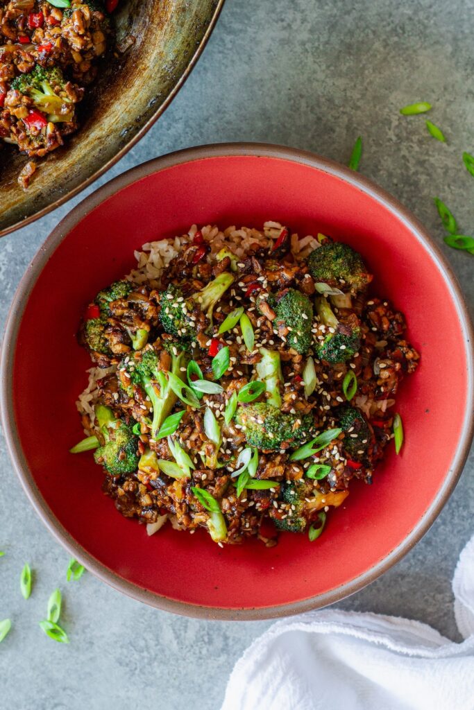 Broccoli tofu stir-fry served over rice with sesame seeds and green onion garnish