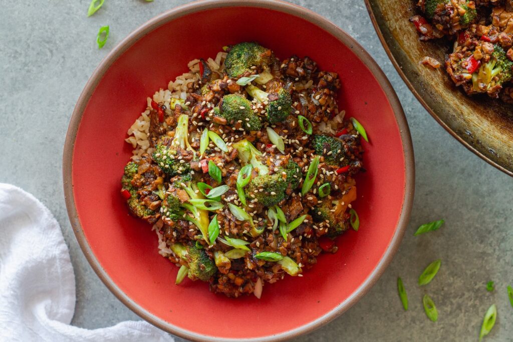 Broccoli tofu stir-fry served over rice with sesame seeds and green onion garnish
