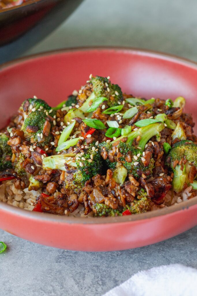 Broccoli tofu stir-fry served over rice with sesame seeds and green onion garnish
