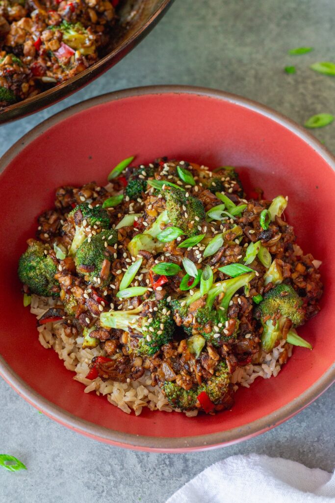 Broccoli tofu stir-fry served over rice with sesame seeds and green onion garnish