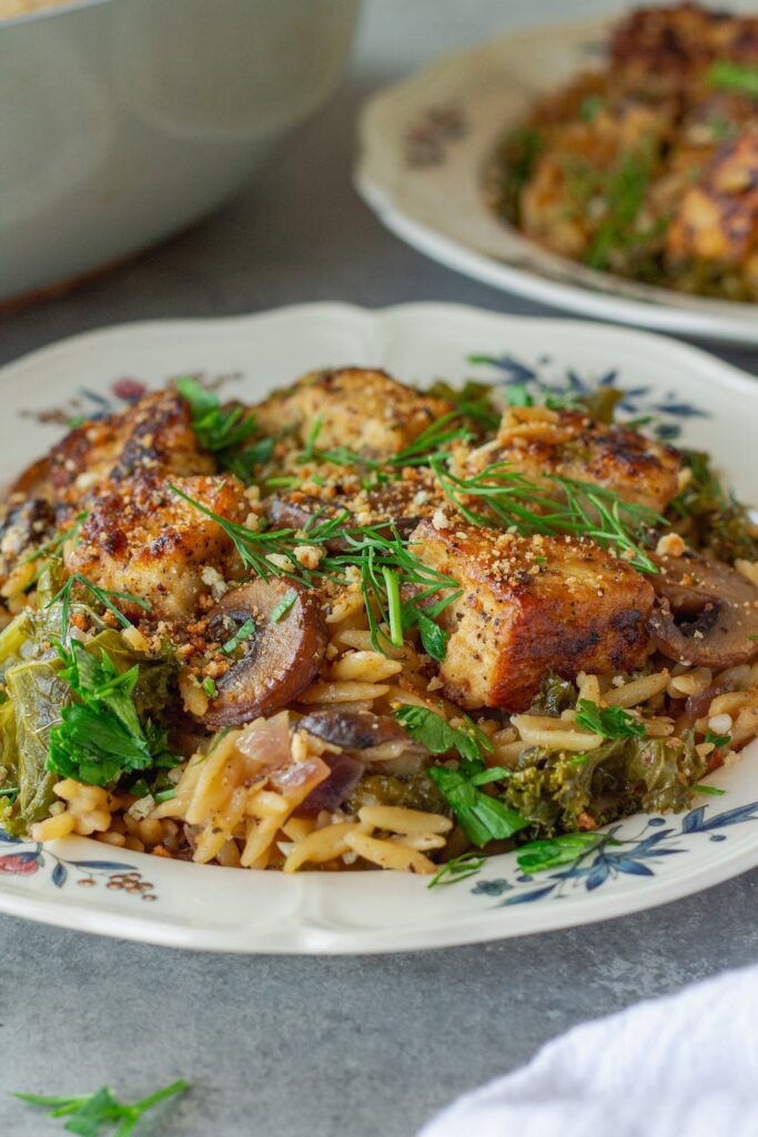 Creamy skillet Dijon orzo with golden crispy tofu cubes, kale, and mushrooms, garnished with fresh dill and breadcrumbs.
