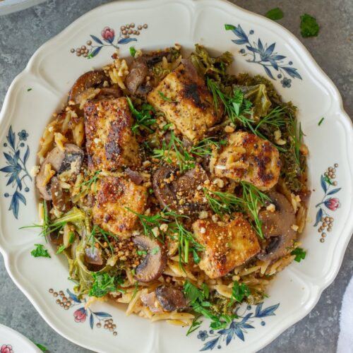 Creamy skillet Dijon orzo with golden crispy tofu cubes, kale, and mushrooms, garnished with fresh dill and breadcrumbs.