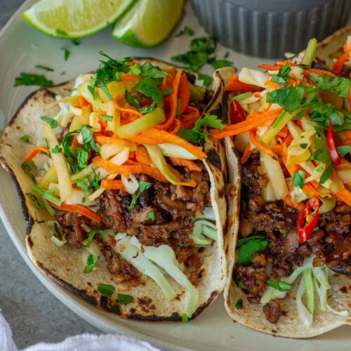 Hoisin-Braised Mushroom and Tofu Tacos topped with fresh slaw and cilantro in warm tortillas