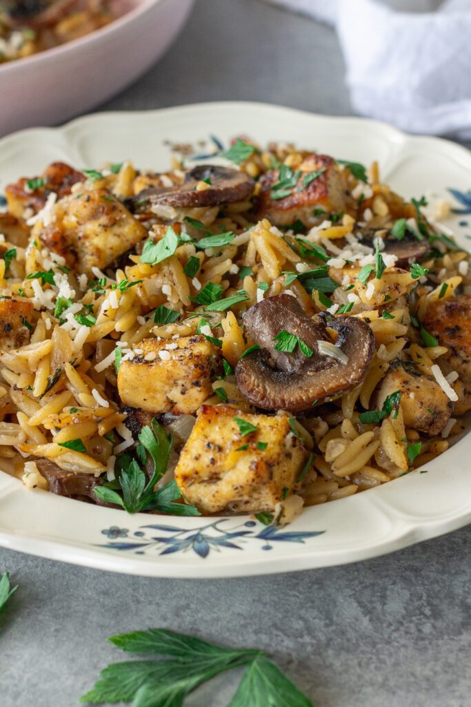 Golden crispy tofu in creamy marsala orzo with mushrooms and fresh parsley garnish.