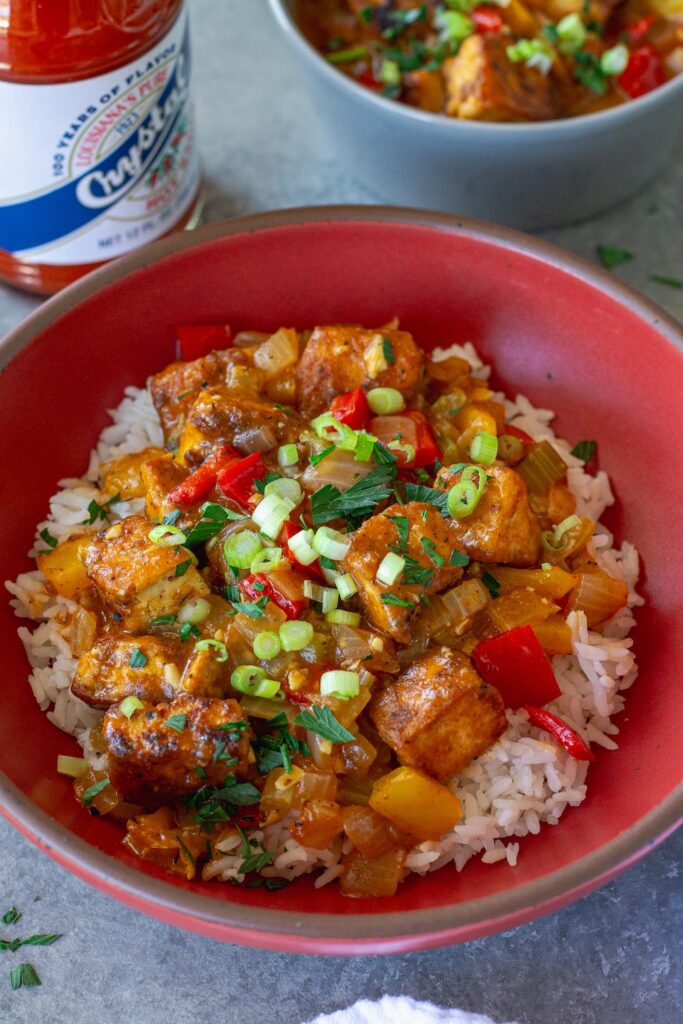 Golden-brown smothered tofu covered in rich gravy over white rice, garnished with green onion, parsley and hot sauce.