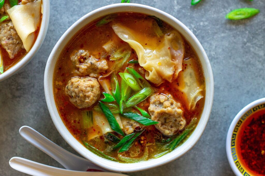 Close-up of vegan wonton meatballs floating in the flavorful broth of the deconstructed soup.