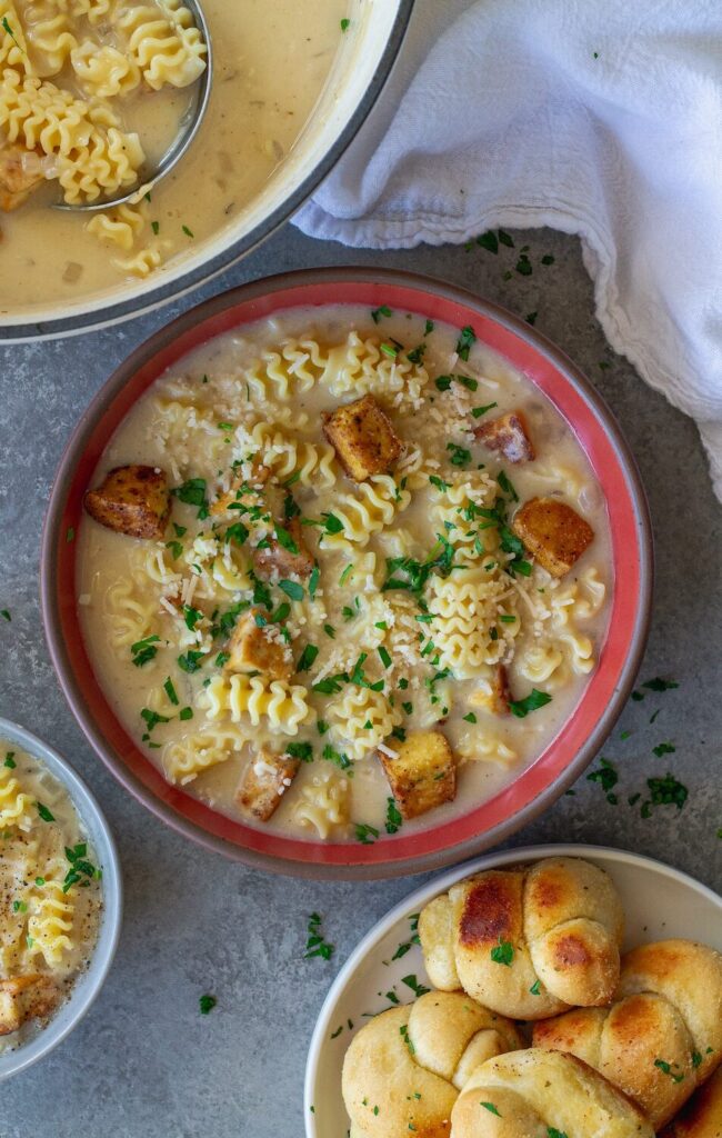 bowl of Vegan Chicken Alfredo Soup with crispy tofu cubes, creamy broth and fresh parsley and parmesan garnish